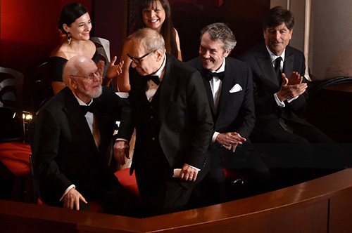 (Left to right) John Williams reaches to embrace Ennio Morricone as Carter Burwell and Thomas Newman look on.