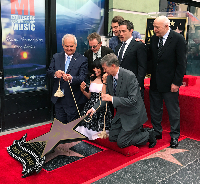 Jerry Goldsmith's star on the Hollywood Walk of Fame revealed. Standing L to R: Lyricist Paul Williams, composer David Newman, Aaron Goldsmith, composer Charles Fox. Kneeling L to R: Hollywood Chamber of Commerce Chair of the Board Jeff Zarrinnam, Carol Goldsmith, Hollywood Chamber of Commerce President and CEO Leron Gubler. 